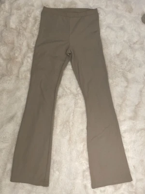 Beige bootcut leggings - Säljer ett par beige leggings med bootcut-modell och hög midja. De är stretchiga och mjuka, perfekta för en chill och trendig look. Passar till sneakers eller chunky boots. Inget synligt märke på leggingsen.