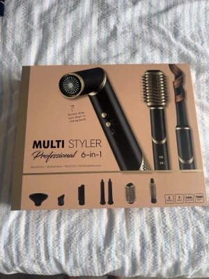 Multi Styler 6-in-1 hårstyler rusta - RustaMulti Styler Professional 6-in-1 är ett svart och guldfärgat stylingverktyg med flera utbytbara tillbehör för att föna, locka och borsta håret. Den har 3 värmeinställningar, 2 hastigheter och cool shot-funktion. Perfekt för dig som vill ha ett mångsidigt stylingverktyg. Oöppnad förpackning 
