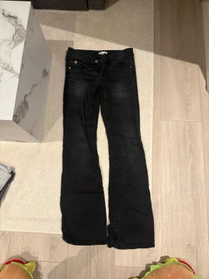 Svarta bootcut jeans från Gina Tricot - Säljer ett par svarta bootcut jeans från Gina Tricot. Jeansen har klassisk femficksmodell, dragkedja och knapp framtill samt subtila slitningar för en cool look. Perfekta till sneakers eller boots.