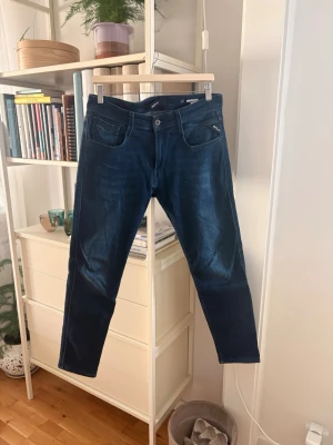 Replay anbass jeans - Snygga marinblå jeans ifrån replay i modellen anbass, tyvärr med 2 små hål vid båda anklarna därav det låga priset.