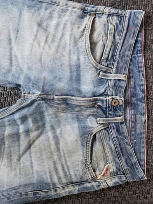 Ljusblå vintage Replay blue jeans - Säljer ett par ljusblå jeans från Replay med snygga slitningar och tvättade detaljer. Klassisk femficksmodell med Replay-logga på bakfickan och patch i läder bak i midjan. W32 L32 men passar W30 helt perfekt! Raka ben och knappgylf. Perfekta för en avslappnad stil.