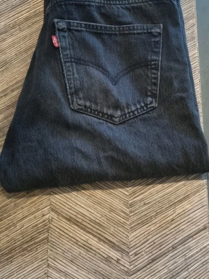 Mörkblå Levi's jeans 34 34 - Säljer ett par klassiska mörkblå jeans från Levi's med rak passform. Jeansen har den ikoniska röda Levi's-lappen på bakfickan och är tillverkade i slitstark denim. Perfekta för en avslappnad och tidlös stil.