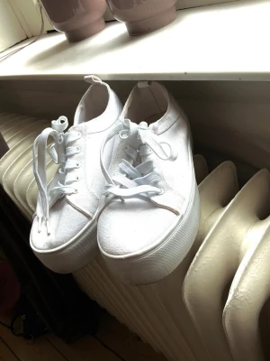Vita platåsneakers från ASOS - Stilrena vita sneakers från ASOS med platåsula och klassisk snörning. Tidlös design med vit yttersula och diskreta detaljer.