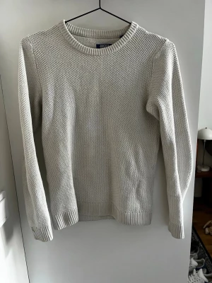 Vit stickad tröja Jack & Jones - Snygg vit stickad tröja från Jack & Jones med rund halsringning och ribbade muddar vid ärmslut och nederkant. Tröjan har en grovstickad struktur som ger en modern look och passar perfekt till jeans eller chinos.