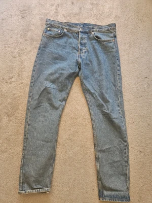 Klassiska raka blå jeans  - Ett par klassiska blå jeans med rak passform och fem fickor. Jeansen har normalhög midja, gylf med dragkedja och knapp samt ljus tvätt. Perfekta för en avslappnad stil och passar till det mesta. Materialet är denim i bomull.