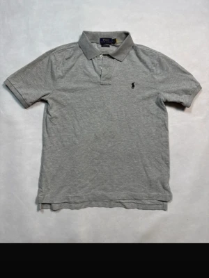 Ralph Lauren piké – grå M - Grå piké från Ralph Lauren i storlek M.  Stilren färg som funkar till allt, perfekt nu till våren/sommaren.  Mycket bra skick. Säljs pga rensning.  Pris: 350 kr (kan diskuteras vid snabb affär)