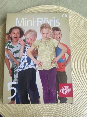 Mini-Röris 5 CD med rörelseövningar - Mini-Röris 5 är en CD med rörelseövningar för barn, perfekt för förskolan eller hemma. Omslaget är färgglatt med barn i olika poser. Skivan är från Friskis & Svettis och hjälper till att göra träning rolig och enkel för yngre barn.