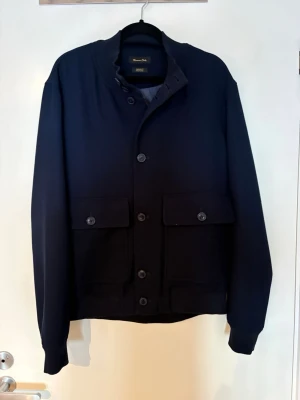 Svart jacka från Massimo Dutti - Stilren svart jacka från Massimo Dutti med klassisk krage och stora fickor framtill. Jackan har knäppning med knappar och är långärmad. Perfekt för dig som gillar en clean och tidlös look. Storlek m| Skick 10/10| Pm för mer info!