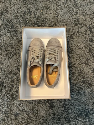 Beige Louboutin sneakers i mocka - Snygga beige sneakers från Christian Louboutin i mjuk mocka med klassiska röda sulor. Lågt skaft och matchande begie skosnören. Perfekta för dig som vill ha en clean och exklusiv look.hör gärna av er vid frågar elelr intresse om olika saker på just min plick.