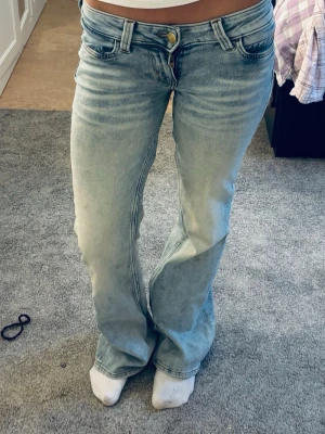 Ljusblå bootcut jeans från cheap monday - Säljer ett par ljusblå bootcut jeans från cheap monday med klassisk femficksmodell och snygga slitningar. Jeansen har låg midja, vida ben och är tillverkade i mjukt denimtyg. Perfekta för en avslappnad och trendig look.