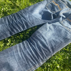 Blå jeans från Nudie Jeans - Säljer dessa sjukt feta Nudie Slim Jim🌊 Skick: 9/10 Storlek (uppskattar): 29/32 Obs! Lappen på storlek och modell är tyvärr bortklippt men enligt chat gpt ska modellen vara Slim Jim men inte 100% säker! Midjan är förstorad, se bild 4  Hör av er vid frågor eller mått!