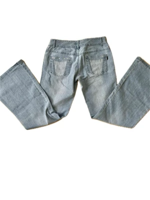 Lågmidjade jeans med detaljer - Ljusblå bootcut jeans 💙  Snygga jeans med utsvängda ben som ger en fin siluett ✨ Låg midja, har jätte fina detaljer med små nitar vid fickorna båda fram och bak, några har lossnat där bak men fortfarande super fina. Storlek 30/33 på jeansen men skriver måtten nedan, motsvarar 36/28. För korta på som är 174:) stretchiga i midjan  Mycket fint skick!  Mått (ca): Midja: 39 cm Innerbenslängd: 77 cm 