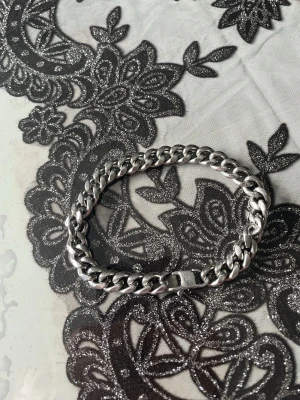 Tungt kedjearmband i silverfärg - Stilrent armband i silverfärgad metall med kraftig kedjelänk. Perfekt för dig som gillar en clean och edgy look. Armbandet har ett robust lås och passar både till streetwear och mer dressade outfits.