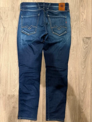 Replay Anbass Hyperflex Mörkblå Jeans W30/L30 Slim Fit - Replay Anbass Hyperflex mörkblå jeans i stretchigt och bekvämt material med clean tvätt, slim fit modell som sitter bra och funkar till allt, storlek W30/L30, midja 40 cm, ytterbenslängd 99,5 cm, benöppning 16 cm, modellen är 185cm & väger 65kg, i fint skick.