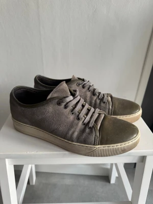 Lanvins  - Snygga sneakers i grått tyg med gröna detaljer på tå och runt snörningen. Skorna har klassisk låg profil, rund tå och matchande grå skosnören. Yttersulan är beige och ger en stilren kontrast. Perfekta för en avslappnad streetstil.