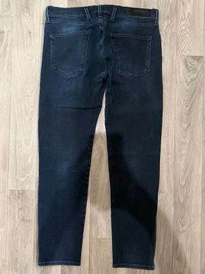 Replay Anbass Hyperflex Marinblå Jeans W30/L30 Slim Fit - Replay Anbass Hyperflex marinblå jeans i stretchigt och bekvämt material, slim fit modell som sitter bra och funkar till allt, storlek W30/L30, midja 41 cm, ytterbenslängd 92,5 cm, benöppning 15 cm, modellen är 185cm & väger 65kg, i fint skick.