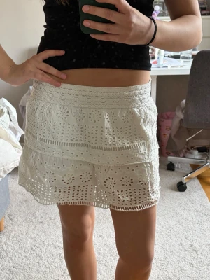 Vit broderad kortkjol med volang - Superfin vit kortkjol med broderade detaljer och volangkant. 