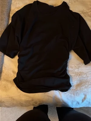 Svart t-shirt från Gina Tricot - En basic svart t-shirt från Gina Tricot i mjuk bomull. Klassisk rund halsringning och korta ärmar. Perfekt att matcha med jeans eller kjol för en enkel och stilren look.