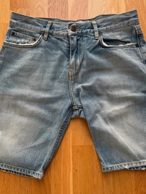 Blå jeansshorts från Dobber - Snygga blå jeansshorts från Dobber. Tillverkade i bomull med slitna detaljer. Storlek W31. 