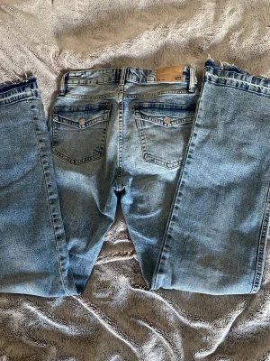 Ljusblå jeans från 157 med råa kanter - Ljusblå jeans från 157 med raka ben. Klassisk femficksmodell med snygga bakfickor med lock och silverfärgade knappar. Jeansen har bälteshällor och är tillverkade i denim av bomull. Jeansen är även midwaist.
