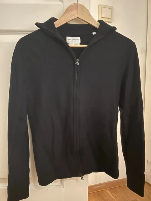 Mörkblå merinoullskofta These Glory Days - Säljer en mörkblå kofta från These Glory Days i Superior Merino. Koftan har hel dragkedja framtill, ribbade muddar och lång ärm. Perfekt för dig som gillar stilrena och bekväma plagg i merinoull. Har krymp i tvätten passar mer xs. Skriv vid funderingar!
