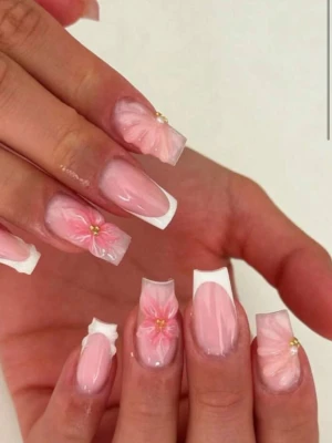 Press-on naglar med rosa blommor - Snygga press-on naglar i ljusrosa med vita franska tippar och 3D-blommor i rosa med gulddetaljer. Naglarna har en rak, fyrkantig form och är perfekta för dig som vill ha en söt och trendig look. Materialet är plast och designen är elegant med fina detaljer.