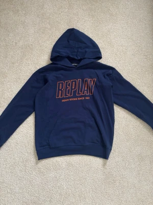 Mörkblå hoodie från Replay - Snygg mörkblå hoodie med oranget tryck från Replay i storlek 166/16 år. Jättefint skick