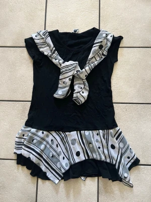 Svart och vit topp storlek M/L -  Svart topp med vit scarf med ränder och prickar.