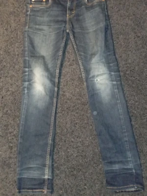 Blå slitna jeans Levi's - Säljer ett par blå skinny jeans med slitningar och ljusa partier på låren och knäna. Jeansen har klassiska fem fickor, kontrastsömmar och är tillverkade i denim. Perfekta för en avslappnad och trendig look.
