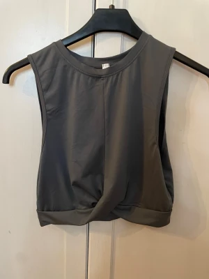 Mörkgrå croppad träningstopp - Snygg mörkgrå croppad linnetopp perfekt anpassad för träning. Toppen är oanvänd men utan prislapp då den tyvärr bara legat i garderoben utan vetenskap om det. Köpt från Lindex för ca 3 år sedan och gjord i syntetmaterial. Pris kan diskuteras. OBS! Köparen står för frakten. 