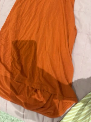 Orange ärmlös linnetopp - Snygg orange linnetopp i mjukt material. Toppen är ärmlös och har en enkel, avslappnad passform som passar perfekt till jeans eller shorts. Perfekt för varma dagar och enkel att styla med accessoarer.