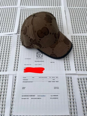 Brun G keps från Gci - Snygg brun keps från Gci med det klassiska G-mönstret i mörkare bruna toner. Kepsen har böjd skärm med svart kant och är tillverkad i ett tåligt tygmaterial. Perfekt för dig som vill ha en stilren accessoar med lyxig känsla.