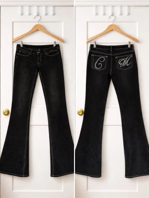 Svarta utsvängda jeans med brodyr - Snygga svarta jeans från week Day med utsvängda ben och kontrastsömmar. På bakfickorna finns vit brodyr med bokstäverna C och M. 