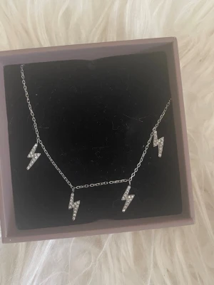 Silverarmband med blixtberlocker - Snyggt silverfärgat armband med fyra blixtformade berlocker dekorerade med små glittrande stenar. Kedjan är tunn och smidig. Nypris 349kr (kolla hemsidan för stormen, denna är i S)