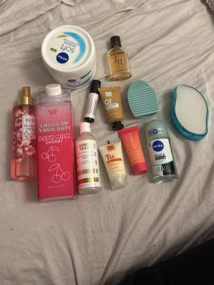 Blandat skönhetspaket med hudvård - Ett skönhetspaket med blandade produkter som body mist med blomdoft, badmjölk med körsbär, Nivea body lotion, deodorant, ansiktsborste i turkos silikon, hårborste, samt flera små tuber och flaskor för hudvård och brun utan sol. Perfekt för dig som vill testa olika märken och dofter.