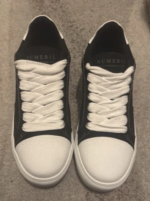 Numeris skor - Stilrena sneakers från Numeris i svart och vitt med chunky vit sula och räfflade detaljer på sidan. Ovandelen är svart med vita kontrastsömmar och tåpartiet är i texturerat vitt material. Nypris 2343kr, svart akryl, pris kan diskuteras vid snabba affärer