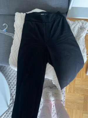 Svarta kostymbyxor Bik Bok - Säljer ett par svarta byxor från Bik Bok med hög midja och vida/raka ben. Byxorna har en enkel och stilren design utan synliga fickor eller detaljer. Byxorna är ganska noppriga annars inga defekter.