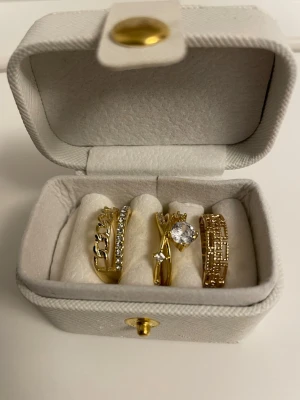 Tre guldpläterade ringar i guld 18k med stenar - Säljer ett set med tre guldpläterade ringar i olika designer. Alla i Copper pläterade med guld 18k. Perfekta för att mixa och matcha till din stil. Justerbara i storleken 