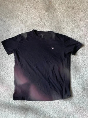 Svart t-shirt från Gant med logga - Säljer en svart t-shirt från Gant med klassisk rund hals och liten broderad Gant-logga på bröstet. T-shirten är i mjuk bomull och har korta ärmar. Enkel och stilren design som passar till det mesta.40kr frakt bitalas av köpare.