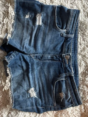 Blå jeansshorts med spetsdetalj - Fina jeansshorts med spets detaljer och coola hål!! Skriv för mått och andra frågor!!🩵 Storlek 158 men passar XS 