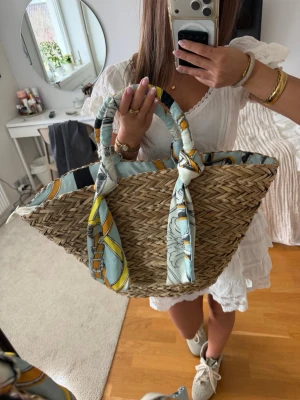 Strandväska med  scarf - Säljer en helt oanvänd strandväska/halmväska med en superfin scarf detalj! Aldrig använd och nypris är 599🥰