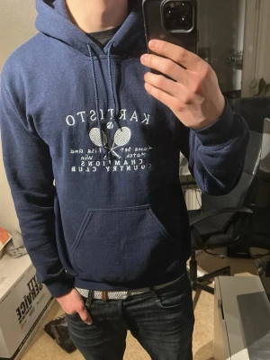 Marinblå Kartisto hoodie med tryck - Snygg marinblå archive hoodie från Kartisto med snyggt vitt tennis tryck framtill, Företaget har slutat sälja så den är bäldigt sällsynt och inte många andra som har likadana. Den är heavy blend vilket gör den bekväm och tålig😊.             A: 49.5cm B: 63.5cm C: 47cm