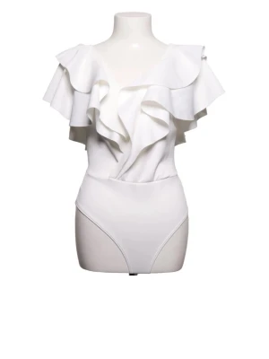 vit volangbody - Stilren vit body med pograderade volanger över axlar och byst. Djup v-ringning ​​både fram och bak soppar till en elegant look. Tillverkad i ett mjukt, stretchigt material som sitter bekvämt mot kroppen. Perfekt för dig som vill ha något extra soppar till outfiten.