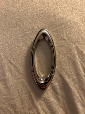 Oakley Ovalformad silverfärgad karbinhake - Snygg oval karbinhake i blankt silverfärgat metallmaterial. Perfekt som accessoar till väskor, nyckelringar eller för att hänga smycken. Modern och stilren design med enkel öppningsmekanism.