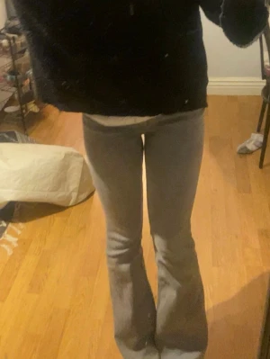 Ljusgrå bootcut jeans - Säljer ett par ljusgrå bootcut jeans med hög midja och utsvängda ben. Jeansen har en klassisk femficksdesign och är tillverkade i ett mjukt denimtyg som sitter snyggt på kroppen. Perfekta för dig som gillar en retroinspirerad look.