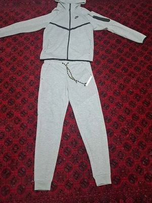 Gråa mjukisbyxor från Nike - Snygga gråa mjukisbyxor från Nike med svart-vitt snöre i midjan och ribbade benslut. Tillverkade i mjukt sweatshirtmaterial som är perfekt för chill dagar. Klassisk Nike-logga på benet och enkel, stilren design.pris kan diskuteras 