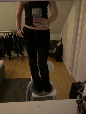 Svarta bootcut jeans - Säljer ett par svarta bootcut jeans med medel midja och klassisk femficksdesign. Jeansen har en snygg passform som framhäver benen och är perfekta till en trendig vardagslook. Materialet känns mjukt och stretchigt för extra komfort.