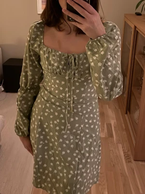 Sommarklänning i grönt - Superfin sommarklänning i grön färg och vita detaljer. Aldrig använd, knytning vid bröstet. Kommer från SHEIN, inköpt för flera år sedan. Perfekt till sommaren!!