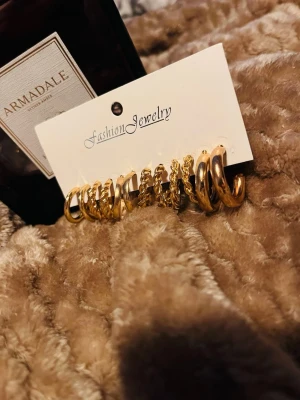 Set med guldiga hoops örhängen - Säljer ett set med flera par guldiga hoops örhängen i olika storlekar och former. Vissa är släta medan andra har tvinnad design. Perfekta för att mixa och matcha till olika looks. Materialet är metall med guldfinish.