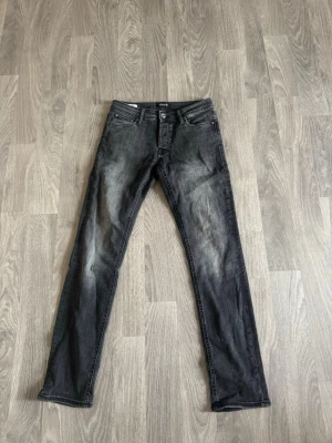 Jack & Jones jeans - Snygga svarta slim fit jeans med diskreta slitningar och tvättade detaljer framtill. Klassisk femficksmodell med dragkedja och knapp. Perfekta för en cool och avslappnad stil.